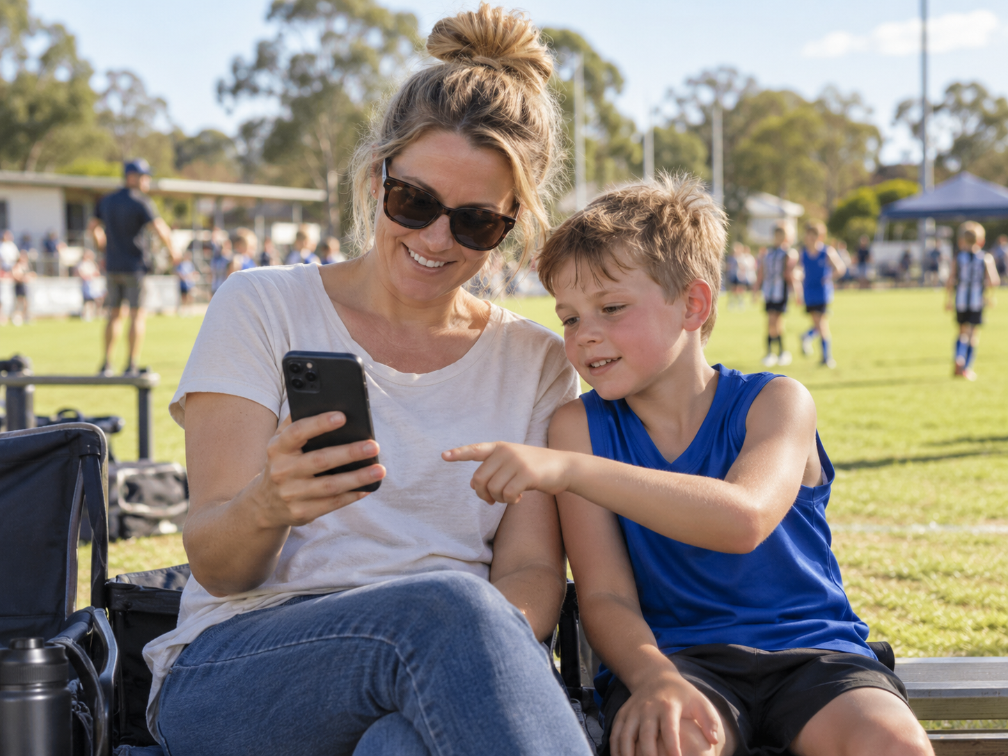 Illustrative photo of a parent ordering on her phone beside a junior sports oval